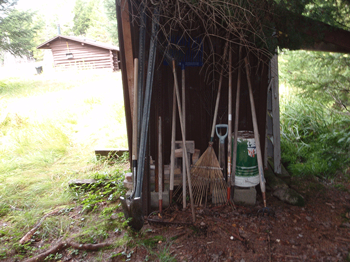An assortment of yard tools are stored at this lean-to.